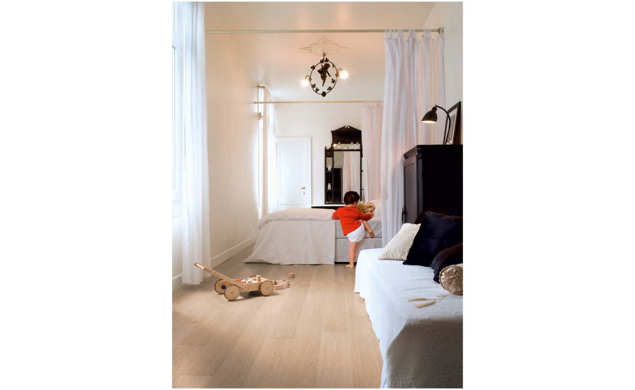 Peuter die in een wit bed klimt op Quick-Step Impressive Wit Geverniste Eik laminaatvloer in slaapkamer