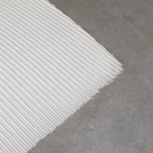 Uitgestreken vloerlijm met strakke lijmribbels op een betonnen vloer als voorbereiding op het leggen van een PVC-vloer